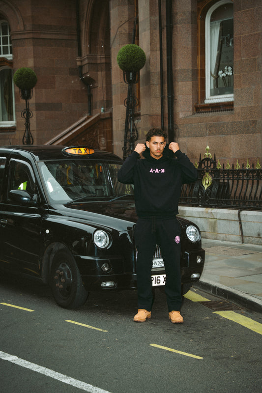 YAK black tracksuit with pink logo details.