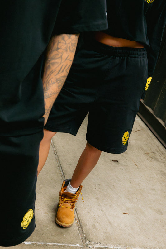 models wearing yak unisex short jogger with baggy fit and yellow logo details. 